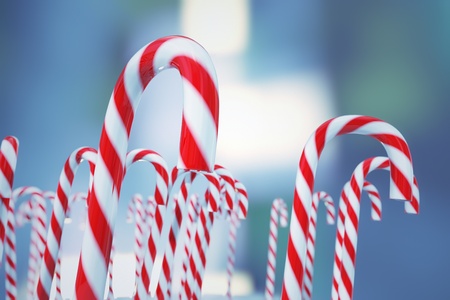 Hard cane-shaped candy sticks with traditional white and red stripes, flavored with peppermint is very popular during Christmas holidays. Blue background.の写真素材