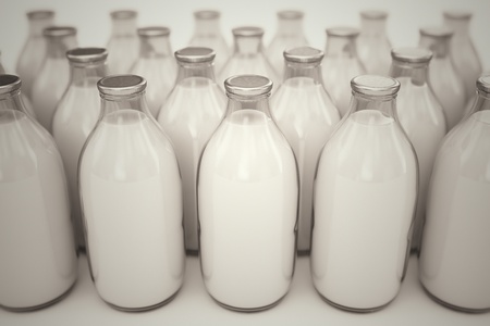 Front shot of old-fashioned glass bottles filled with milk on a white backround. Perfect for any health or natural nutricion realted purposes.の写真素材