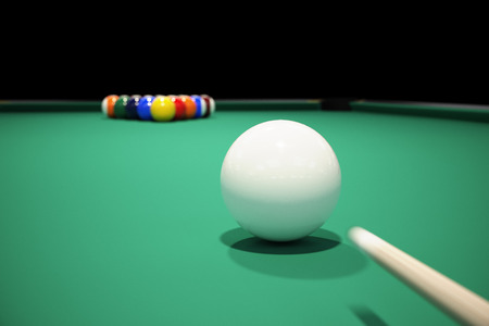 Billiard balls on the green baize of a billiard table. Breaking the rack in pool.Strong shot of cue...
