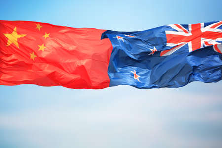 Chinese and New Zealand flags amid blue skiesの写真素材