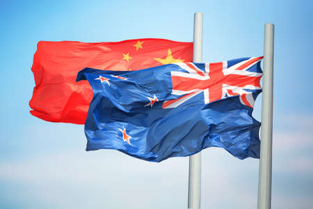 Flags of New Zealand and China amid blue skiesの写真素材