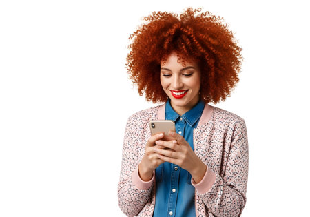 Portrait of a happy young woman with afro hairstyle using mobile phone isolated on white backgroundの素材