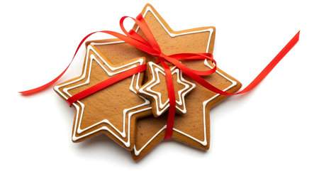 a stack of star shaped gingerbread cookies tied together with a bright red festive ribbon on whiteの素材