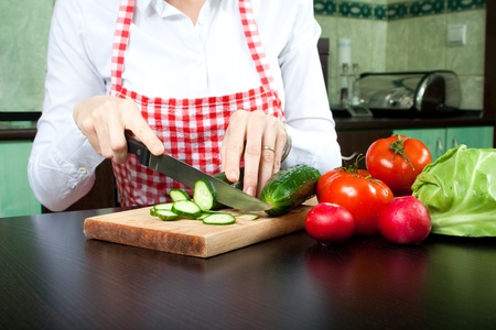Young woman chops vegetable saladの写真素材
