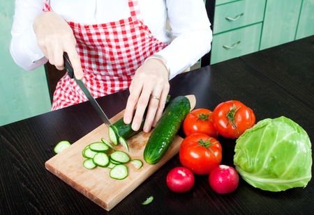 Young woman chops vegetable saladの写真素材