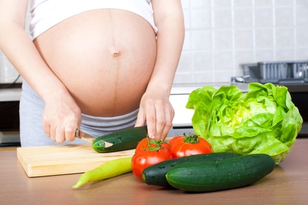 Pregnancy and nutrition - pregnant woman with vegetables on desk の写真素材