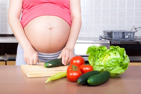 Pregnancy and nutrition - pregnant woman with vegetables on desk の写真素材