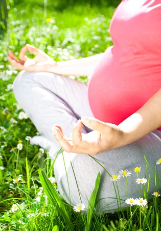 Beautiful pregnant woman relaxing in the park, yoga の写真素材