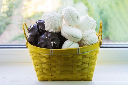 Yellow basket with marshmallow on the windowsillの写真素材