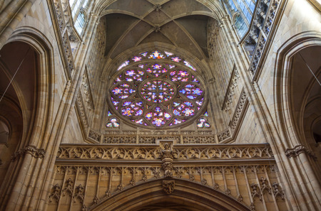 A fragment of the arched ceiling and walls with bas-reliefs and stained-glass window in one of the medieval Catholic churches in Prague Czech Republicのeditorial素材