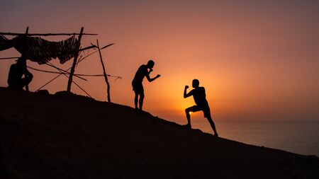 Silhouettes of friends jumping on a beach at sunsetの写真素材