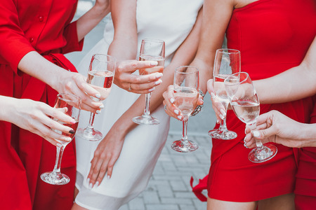 Beautiful young girls in red dresses are celebrating a bachelorette party and drink champagneの写真素材