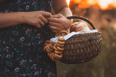 Beautiful young woman with a basket full of fresh baked bread.の写真素材