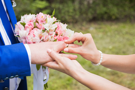 wedding rings and hands of bride and groom. young wedding couple at ceremony. matrimony. man and woman in love. two happy people celebrating becoming familyの写真素材