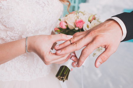 wedding rings and hands of bride and groom. young wedding couple at ceremony. matrimony. man and woman in love. two happy people celebrating becoming familyの写真素材