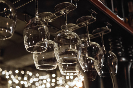 Wine glasses in shelf above a bar rack in restaurant.の写真素材