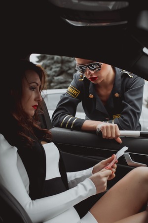 Young beautiful police woman stops car for checking driver