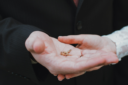 wedding rings and hands of bride and groom. young wedding couple at ceremony. matrimony. man and woman in love. two happy people celebrating becoming familyの写真素材