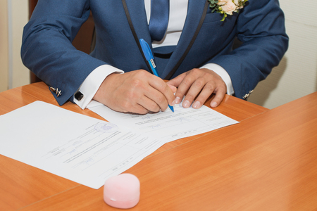 Young couple signing wedding documents. Focus on hand.の写真素材