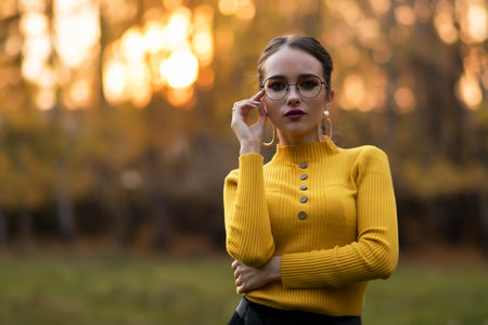 Charming young woman standing in autumnal parkの写真素材