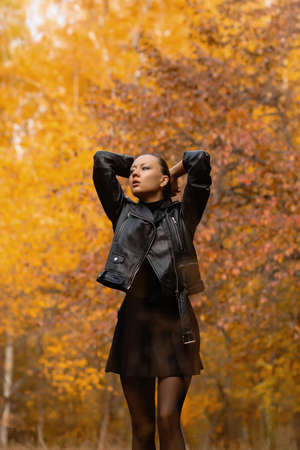 Seasonal autumn fashion. Modern young woman wearing fashionable warm clothes posing in the autumn park.の写真素材