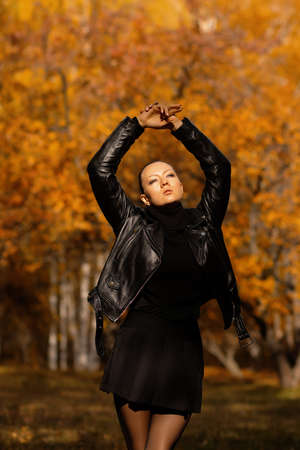 Seasonal autumn fashion. Modern young woman wearing fashionable warm clothes posing in the autumn park.の写真素材