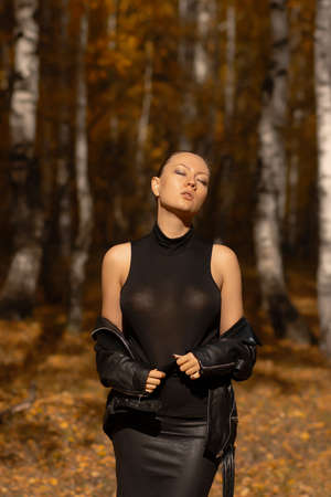 Seasonal autumn fashion. Modern young woman wearing fashionable warm clothes posing in the autumn park.の写真素材