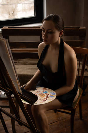 Nude woman painting on canvas in studioの写真素材