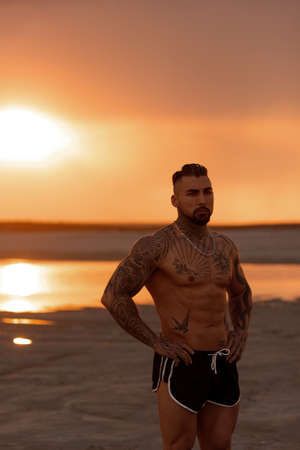 Handsome young muscular italian man posing shirtless on the beach, sunset summer time. Ideal fit body.の写真素材