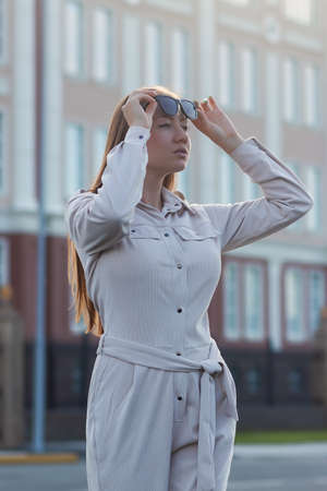 Beautiful young businesswoman standing in the city street. Trendy business fashion lady in glasses looking away posing outdoorsの写真素材