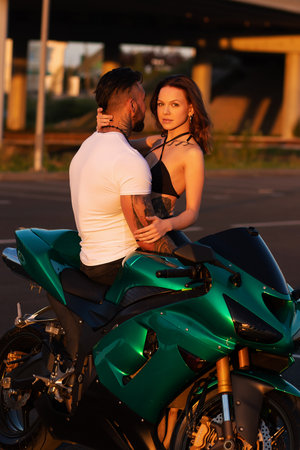 Couple hugging near motorbike at sunsetの写真素材