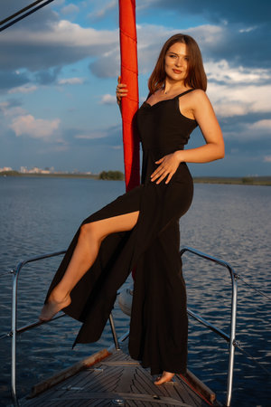 Gorgeous fit woman standing on yacht deck and admiring sea at sunsetの写真素材