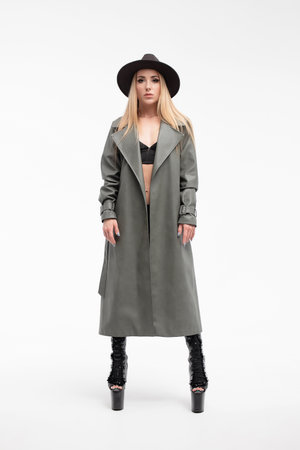Sensual young lady in lingerie and coat looking at camera in studioの写真素材