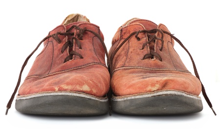Pair of very worn old leather dress shoes isolated on whiteの写真素材