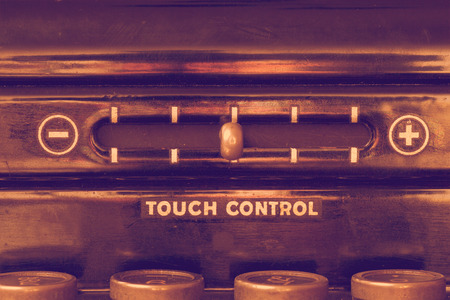 Close up of vintage typewriter front panel with touch control lever and the tops of four keys in muted warm purple and gold huesの写真素材