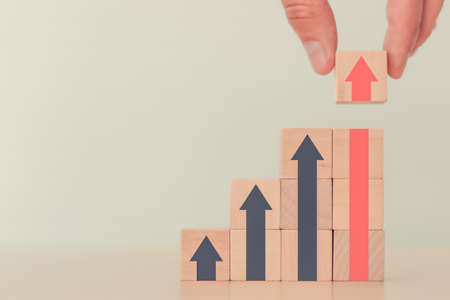 Business man hand try to arranging block wood to arrow up which step up stair. business growth with...