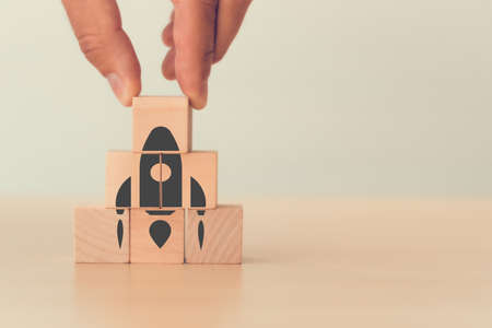 Hand man put arranging with rocket on the wooden cube block for meaning start up, goal, new idea project conceptの写真素材