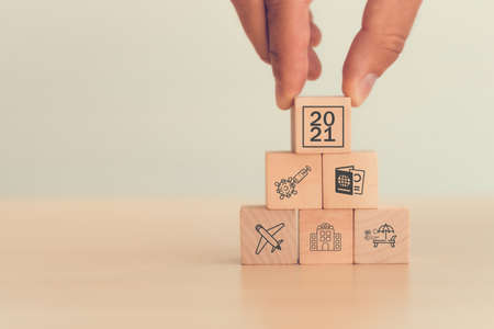 The hand put wooden block wording year 2021 with vaccination icon, travel icon, vaccination certification. The target for travel and lifestyle concept after the people get the vaccination.の写真素材