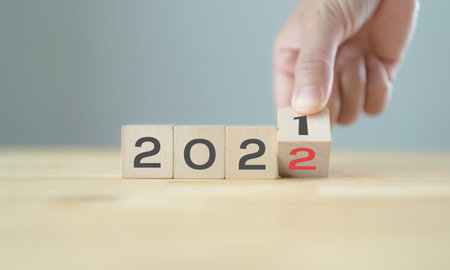 Businessman hand holding wooden cube with flip over block years 2021 to 2022 Plans word on table...