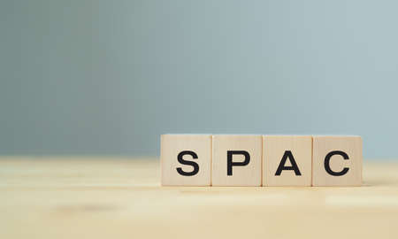 SPAC symbol. Wooden cubes with words SPAC, special purpose acquisition companies' on beautiful grey...