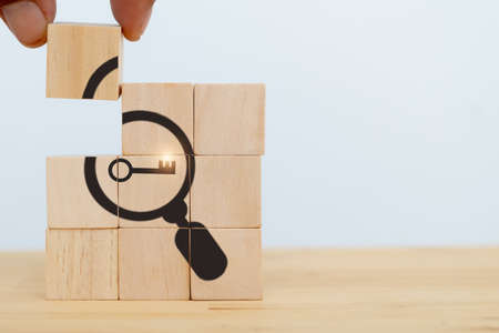 Finding solutions concept. Business problem solving and make decision. New ideas and innovation. Team brainstorming to set strategies. Hand holds wooden cubes with magnifying glass and key icon.の写真素材