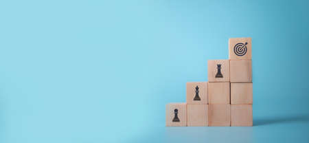 Business goals and strategies concept.  Change and strategy management for business adaptation and growth. The top of wooden cubes with "GOAL" icon standing with other "STRATEGIES" on blue background.の写真素材