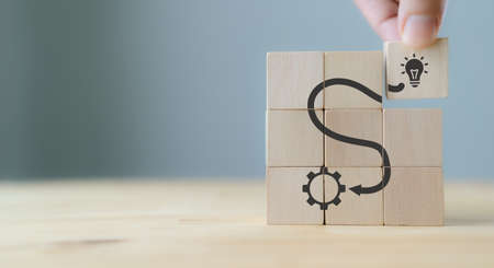 Idea and solution concept.Creative and innovation inspiration. Brainstorming to improve and develop the performance. Hand puts wooden cubes with idea and execution icon on grey background , copy spaceの写真素材