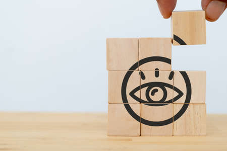 Company vision concept. Businessman put the wooden cubes with "VISION"  symbol on beautiful white background and copy space. Banner for symbols of vision, leadership, strategy, foresee, objectives.の写真素材