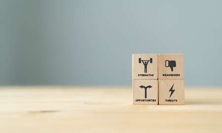 Concept of SWOT analysis and strategic planning technique. Strengths, weaknesses, threats and opportunities of company. SWOT symbols on wooden cubes with beautiful grey background and copy space.の写真素材