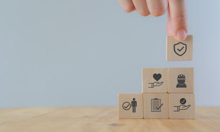 Safety at work concept. Hand holds wooden cube with safety icons; safety first, protections, health, regulations and insurance.  Used for banner, beautiful bright background and copy space.の写真素材