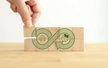 Green eco infinity, net zero, circular economy, renewable energy and save world concept. Sustainable development.  Hand puts wooden cubes with green econ infinity on white background. Eco banner.の写真素材
