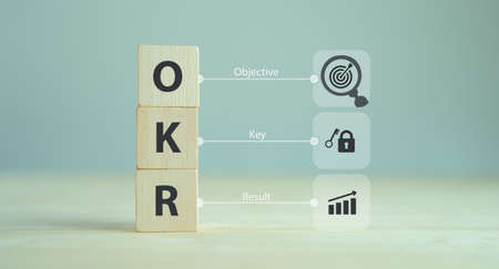 OKR text (Objectives, Key and Results) wooden cube block on grey background. Business target and drive business and performance. Focused on common goals. Achieve business growth by flexible managementの写真素材