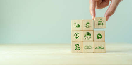Net zero and carbon neutral concept. Net zero greenhouse gas emissions target. Climate neutral long term strategy.  Putting wooden cubes with green net zero and save world icon on grey backgroud.の写真素材