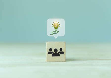 Suggestion and consulting concept. New idea, solution. Wooden cubes with holding light bulb and teamwork icon on grey background and copy space. Business review, strategy suggestion for business.の写真素材